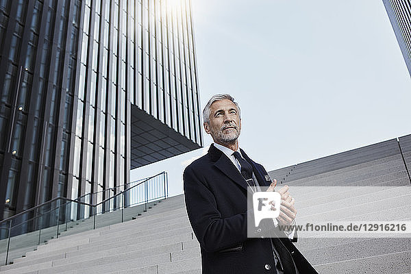 Portrait of mature businessman standing on stairs outdoors