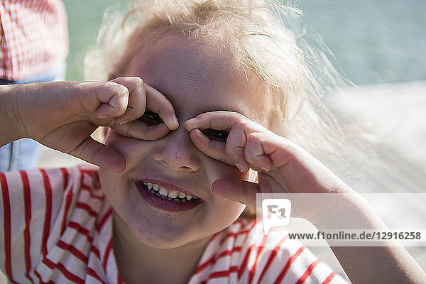 Portrait of happy girl making finger glasses