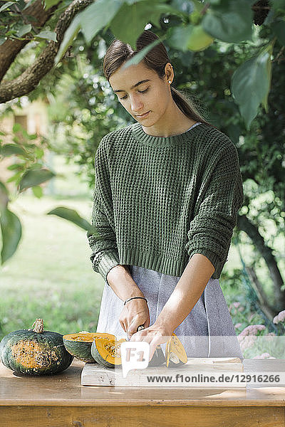 Young woman cutting pumpkin for preparing gnocchis