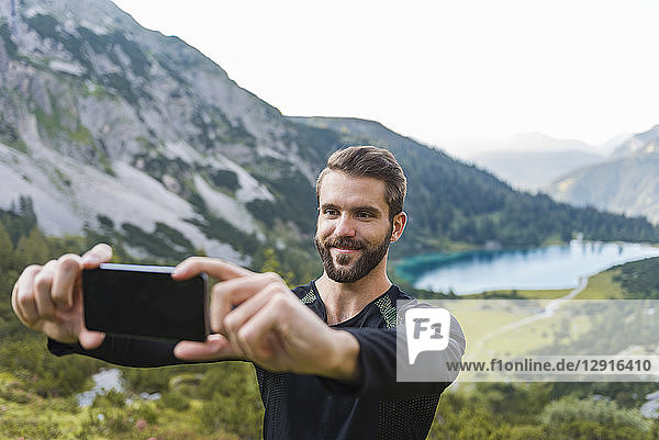 Austria  Tyrol  Hiker taking selfies with his smartphone at Lake Seebensee