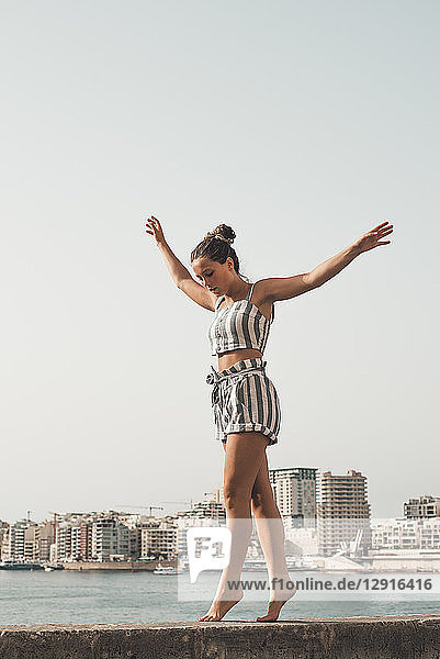 Teenage girl wearing striped beach wear  balancing on wall
