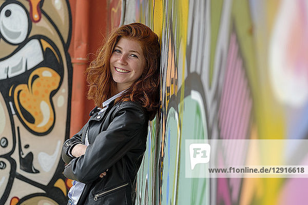 Italy  Finale Ligure  portrait of smiling teenage girl leaning against mural