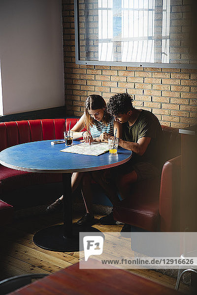 Young couple sitting at table in a cafe with map