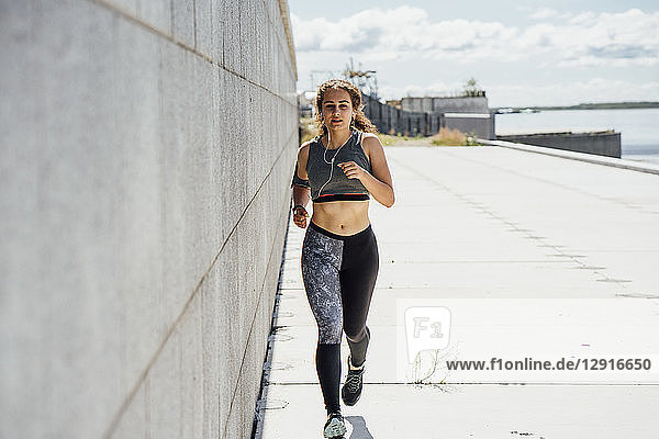 Young athletic woman running along a wall