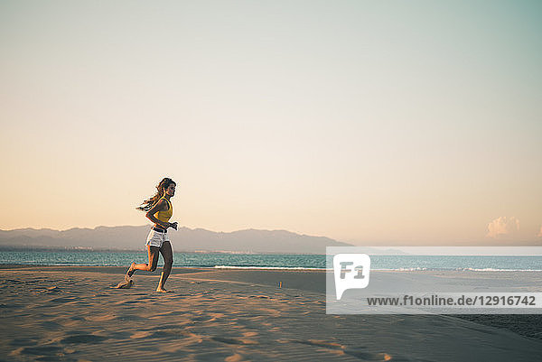 Teenage girl running on the beach at sunset