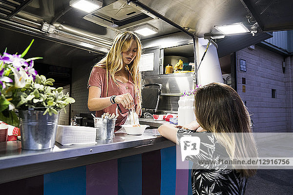 Young woman in a food truck serving customer