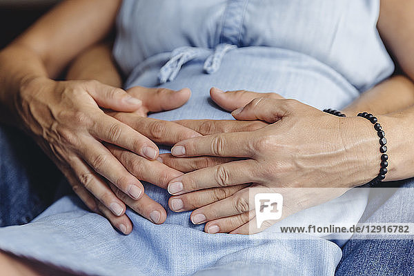 Hands of mature man and his pregnant mature wife touching her belly