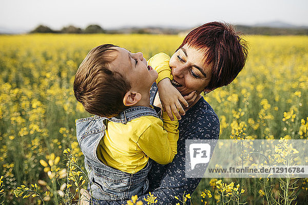 Mother having fun with her little son in a rape field