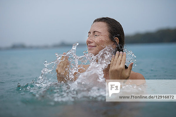 Young woman bathing in lake splashing with water