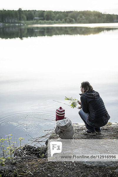 Finland  Kuopio  mother and daughter crouching at a lake