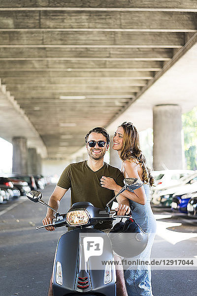 Happy couple with motor scooter at underpass