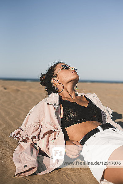 Fashionable teenage girl lying on the beach