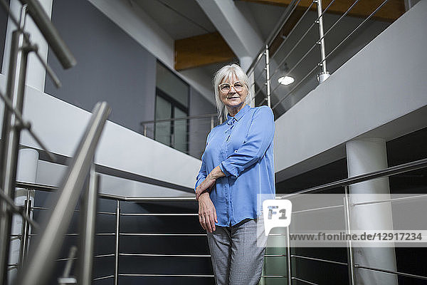 Smiling senior businesswoman standing on office hallway