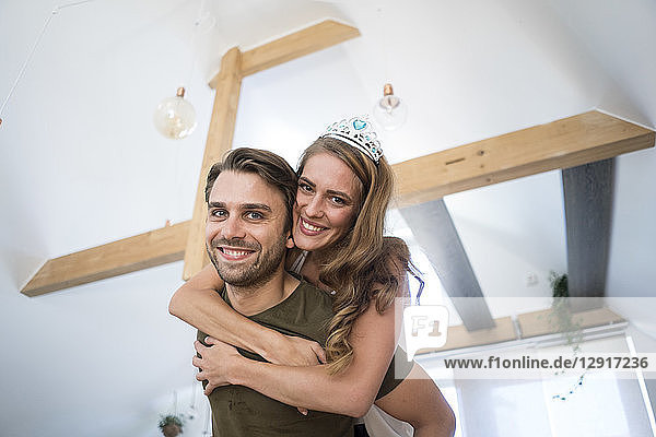 Portrait of happy couple at home with woman wearing tiara
