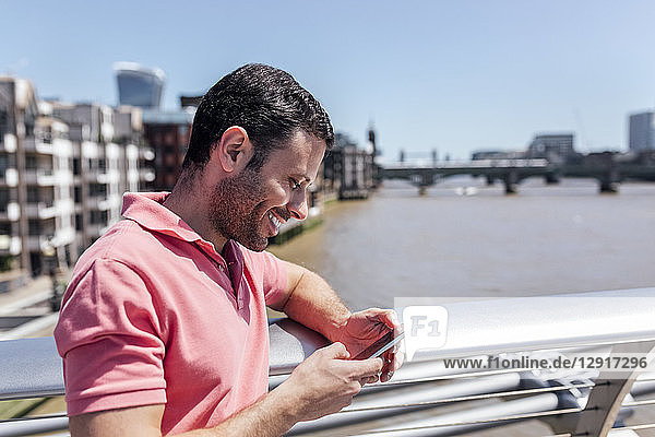 UK  London  man using his smartphone on the Millennium Bridge