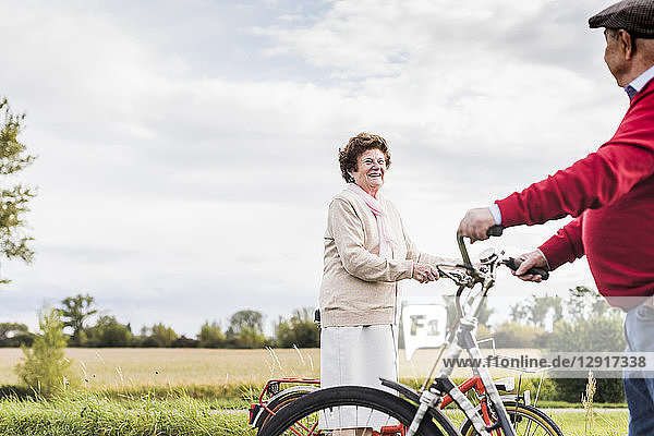 Senior man and woman with bicycles meeting in rural landscape