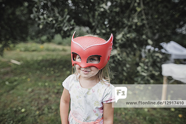 Portrait of smiling little girl wearing red mask