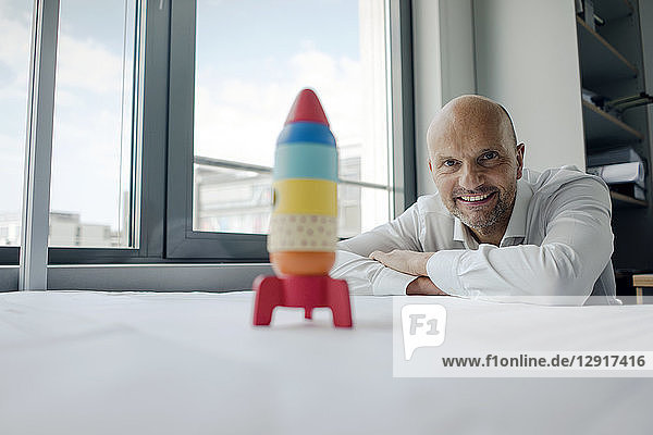 Businessman playing with toy rocket in office