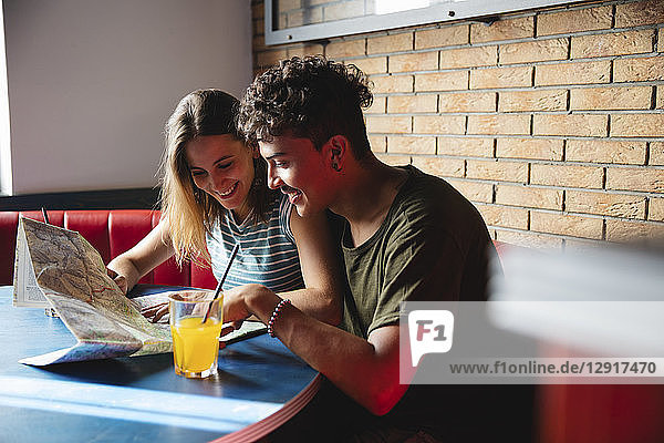 Smiling young couple sitting at table in a cafe with map