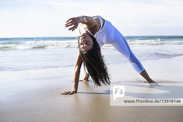 Foto einer jungen Frau beim Yoga am Strand