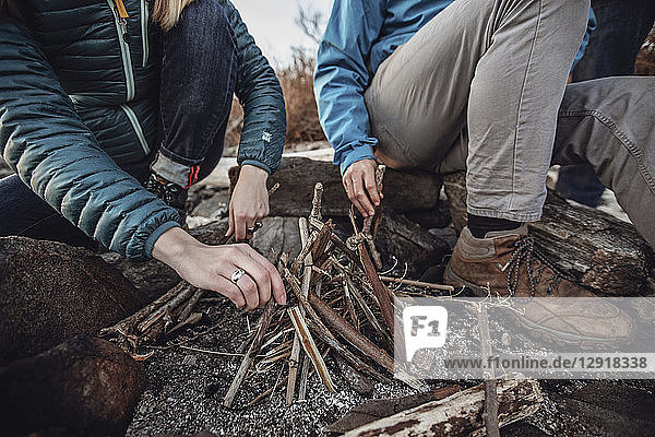 Low section of young man and woman arranging sticks into small campfire  Portland  Maine  USA