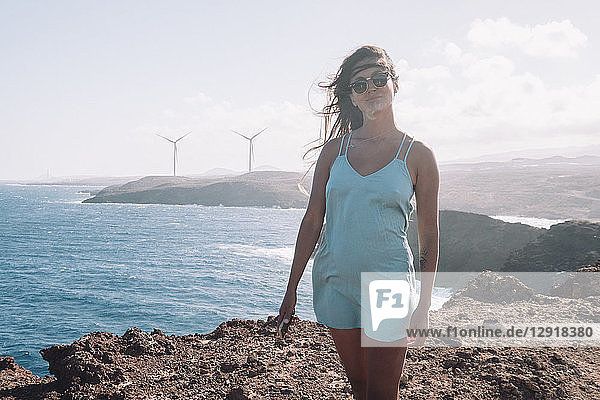 Frau auf dem Gipfel eines zerklüfteten Berges mit Blick auf das Meer und eine Windmühle  Teneriffa  Kanarische Inseln  Spanien
