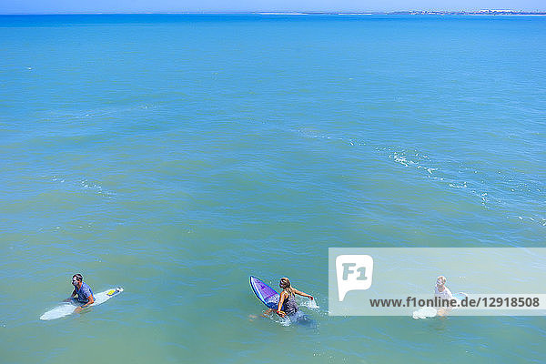 Zwei männliche und eine weibliche Surferin im Meer