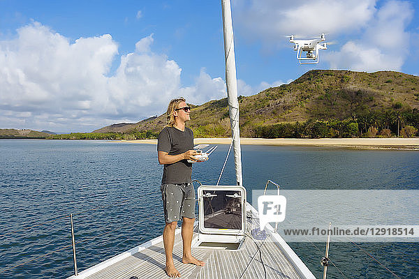 Full length shot of man flying drone on yacht