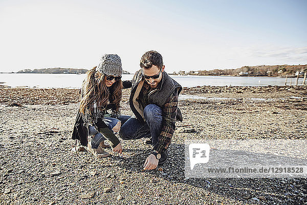 Couple looking for sea glass along beach  Peaks Island  Maine  USA