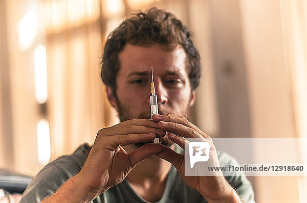 View of single young man holding syringe with vaccine