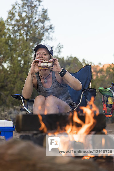 Eine Frau hält einen S'Äômores vor einem Lagerfeuer im Zion National Park  Utah.