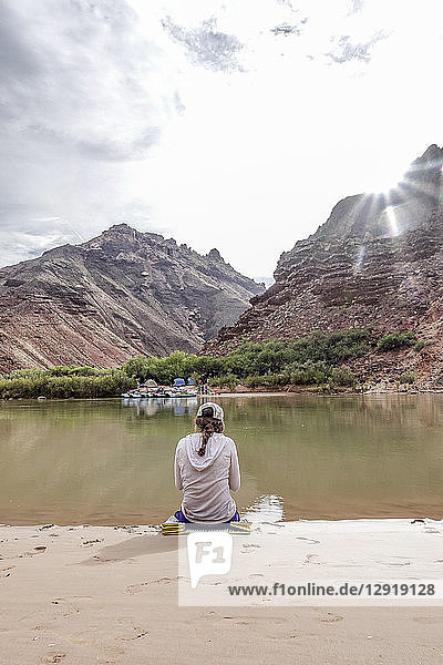 Rückansicht einer Wanderin  die am Ufer des Colorado River im Grand Canyon  Arizona  USA  sitzt