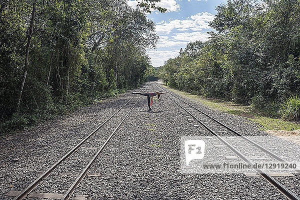 Junge Frau auf einem Bein stehend zwischen leeren Eisenbahnschienen im Iguazu Falls National Park  Parana  Brasilien