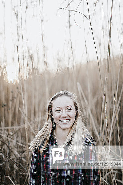 Lachende junge Frau  die vor langem Gras im Herbst steht  Peaks Island  Maine  USA