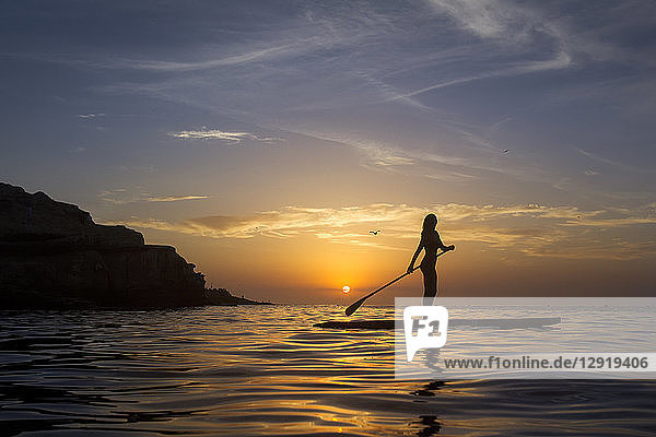 Side view of woman paddle boarding ion Pacific Ocean at sunset  La Jolla  San Diego  California  USA