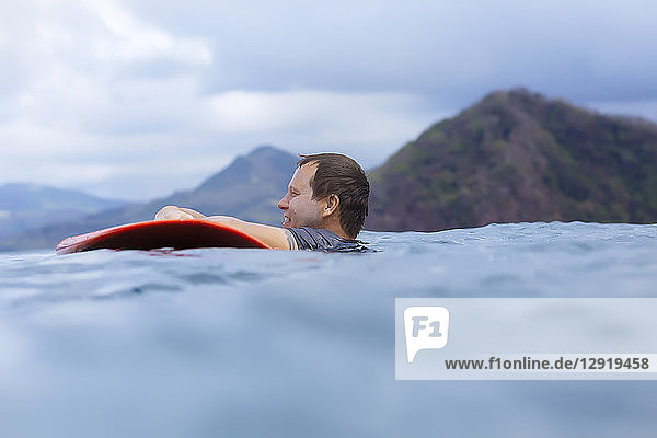 Seitenansicht eines Mannes mit Surfbrett im Meer