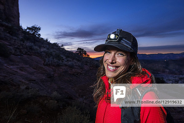 Porträt einer Wanderin mit Stirnlampe  die am Cathedral Rock steht und in die Kamera lächelt  Arizona  USA