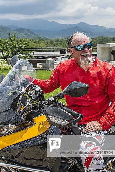 Lächelnder älterer Mann mit Bart auf einem Motorrad sitzend  Nan  Mueang Chiang Rai District  Thailand