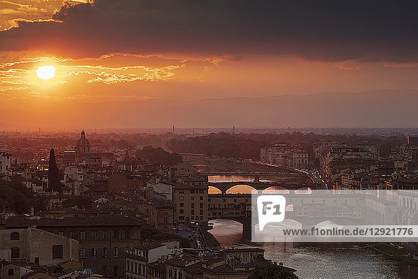 Sun setting behind the city of Florence with the Ponte Vecchio and Ponte Santa Trinita bridges over the Arno River  Florence  Tuscany  Italy
