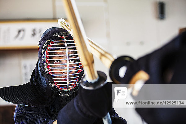 Close up of Japanese Kendo fighter wearing Kendo mask in combat pose.