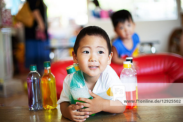 Junge mit einer Flasche mit grüner Flüssigkeit in der Hand in einer japanischen Vorschule.