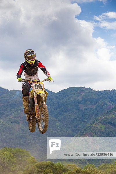 Motocross Driver jumping with mountains and clouds in the background. Colombia. South America.
