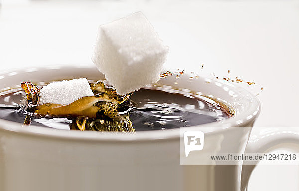 Zuckerwürfel  die in eine Tasse Kaffee fallen