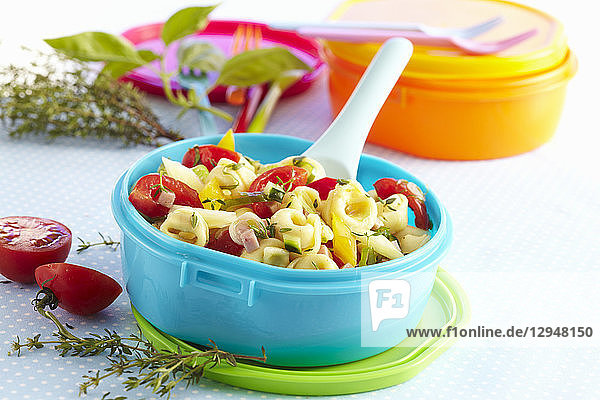 Bunter Tortellini-Salat in einer Tupperware-Schale mit Tomaten und frischen Kräutern