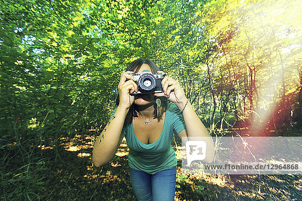 Junge Frau im Wald mit einer Kamera.