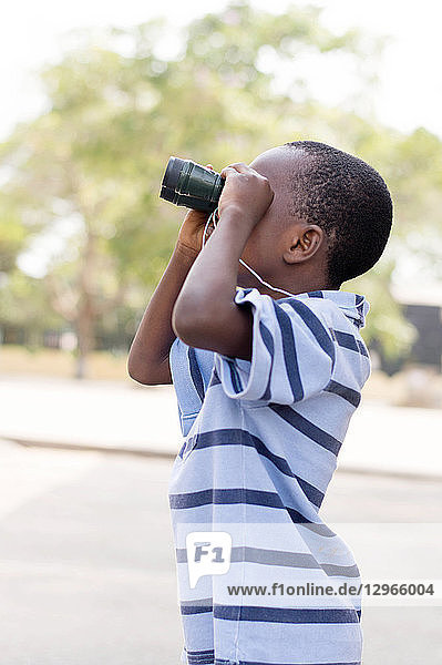 Kind schaut durch das Fernglas  um sein Ziel zu suchen.
