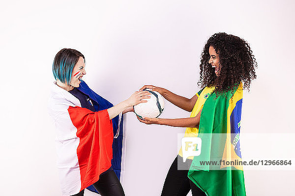 Portrait of two young French and Brazilian fans pulling a balloon