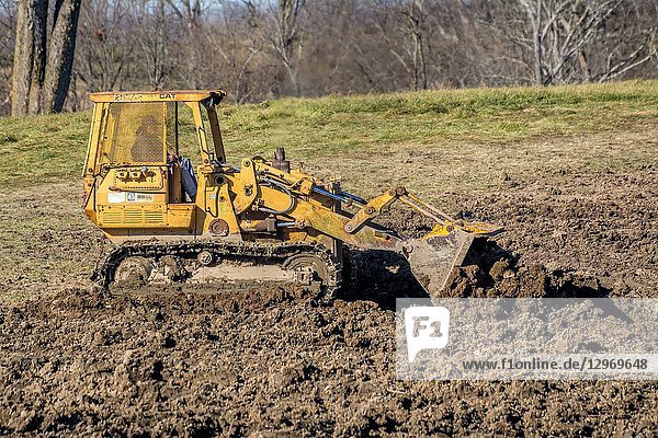 Dozer scoop equipment spreading dirt in a sinkhole in Kentucky USA.