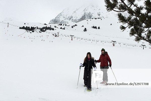 Baqueira Beret  Ski resort  Pyrenees  Aran Valley  Lleida  Catalonia  Spain. Line of people walking with snow rackets towards the summit of a snowy hill.