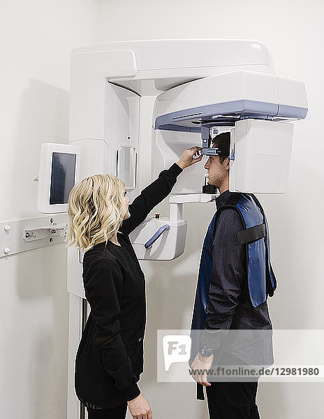 Dental nurse adjusting x-ray machine for patient